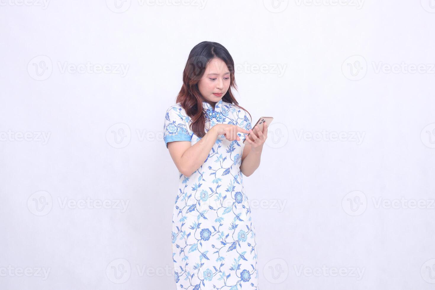 young asian javanese chinese woman wearing left sided chinese blue dress while operating gadget forefinger pressing cell phone isolated white background photo