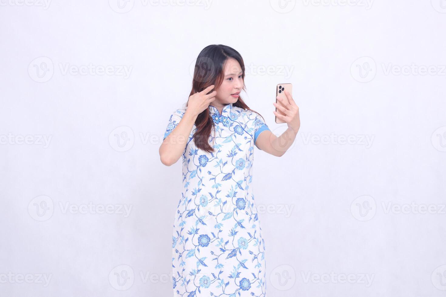 Young Asian Chinese Javanese woman wearing a left-slanted Chinese blue dress while operating a glass gadget isolated on a white background photo