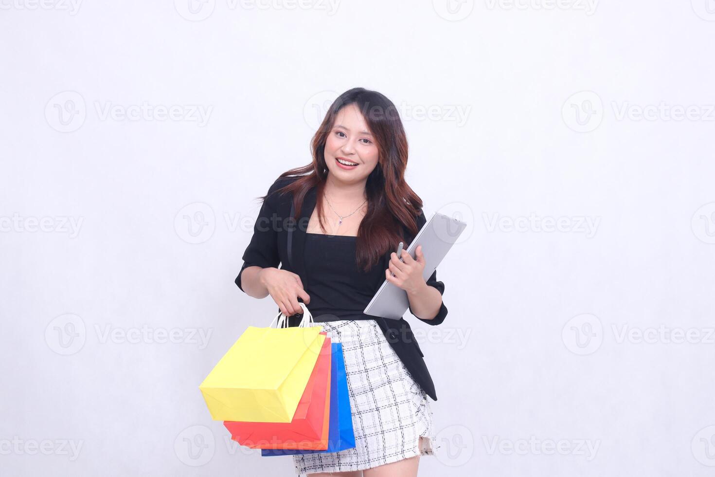 young beautiful girl customer 20s formal office cheerful smile tilted holding tablet pen and carrying shopping paper bag isolated white background photo