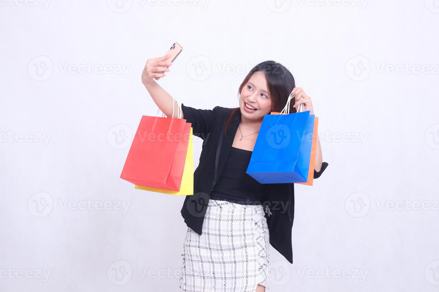 beautiful young woman customer 20s formal office smiling happily while taking photo in front of cell phone up hand showing order while carrying shopping paper bag isolated white background
