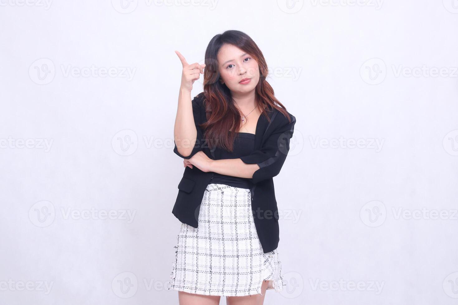 Beautiful Asian Indonesian girl 20s formal office flat arms folded pointing to top right isolated white background photo