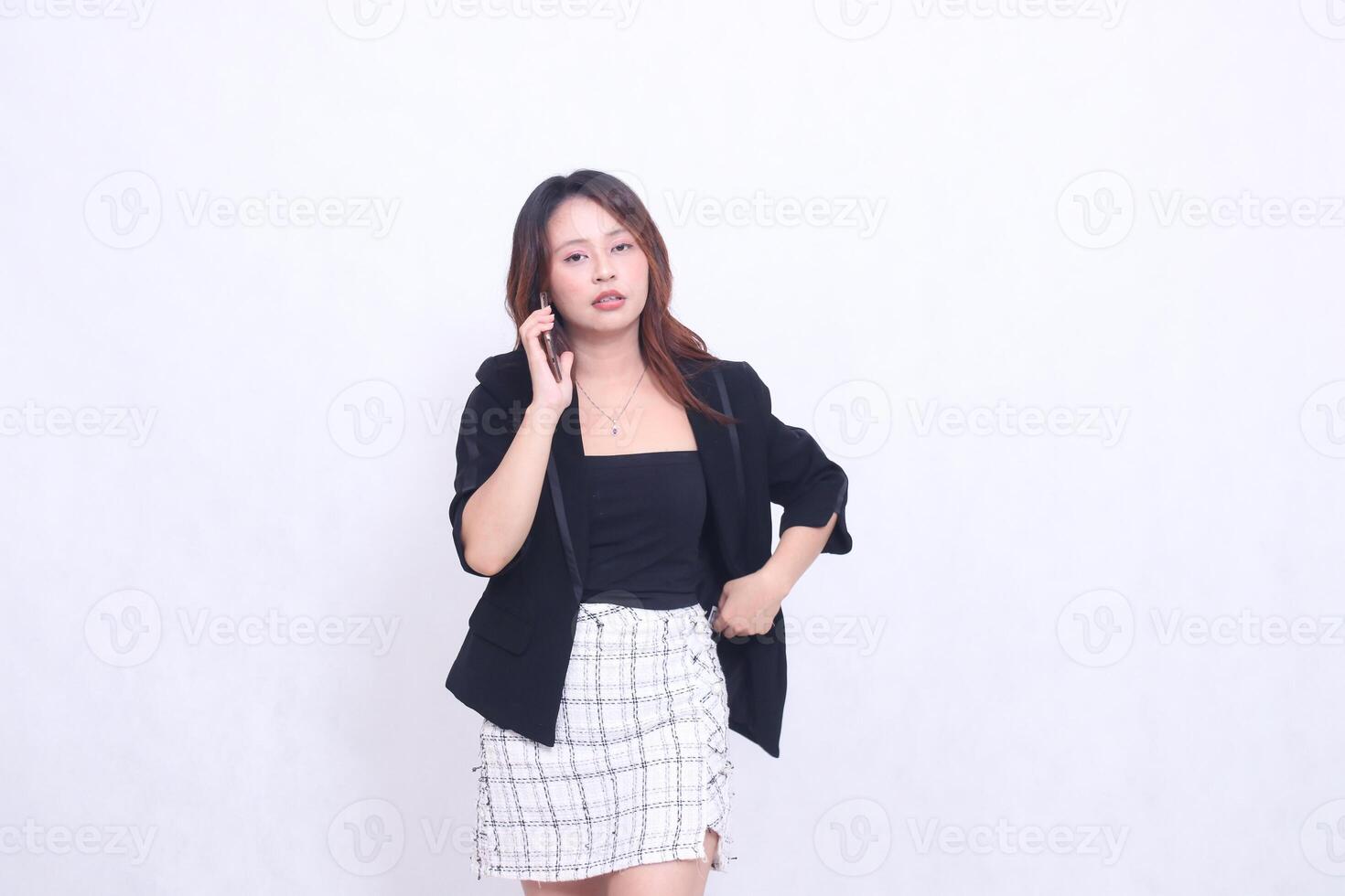 Beautiful Indonesian office woman in her 20s with a weak expression on the phone using her cellphone gadget, cream color for promotions, isolated on a white background photo