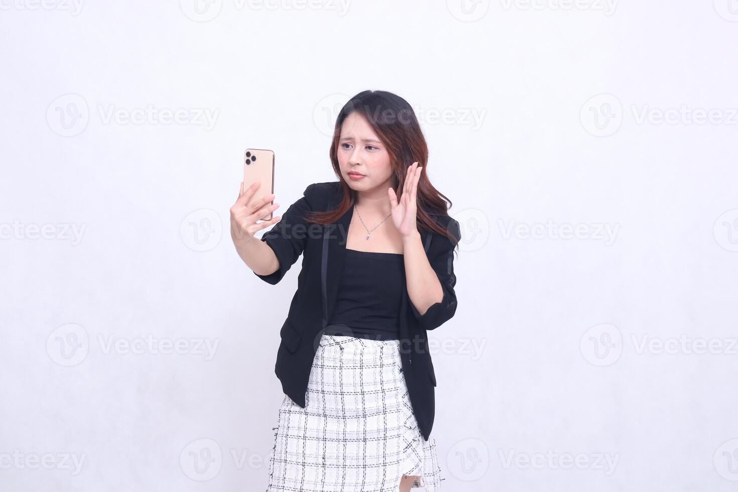 beautiful Indonesian office woman in her 20s with a sad expression looking at her cream colored cellphone gadget while making a call for a promo isolated on a white background photo