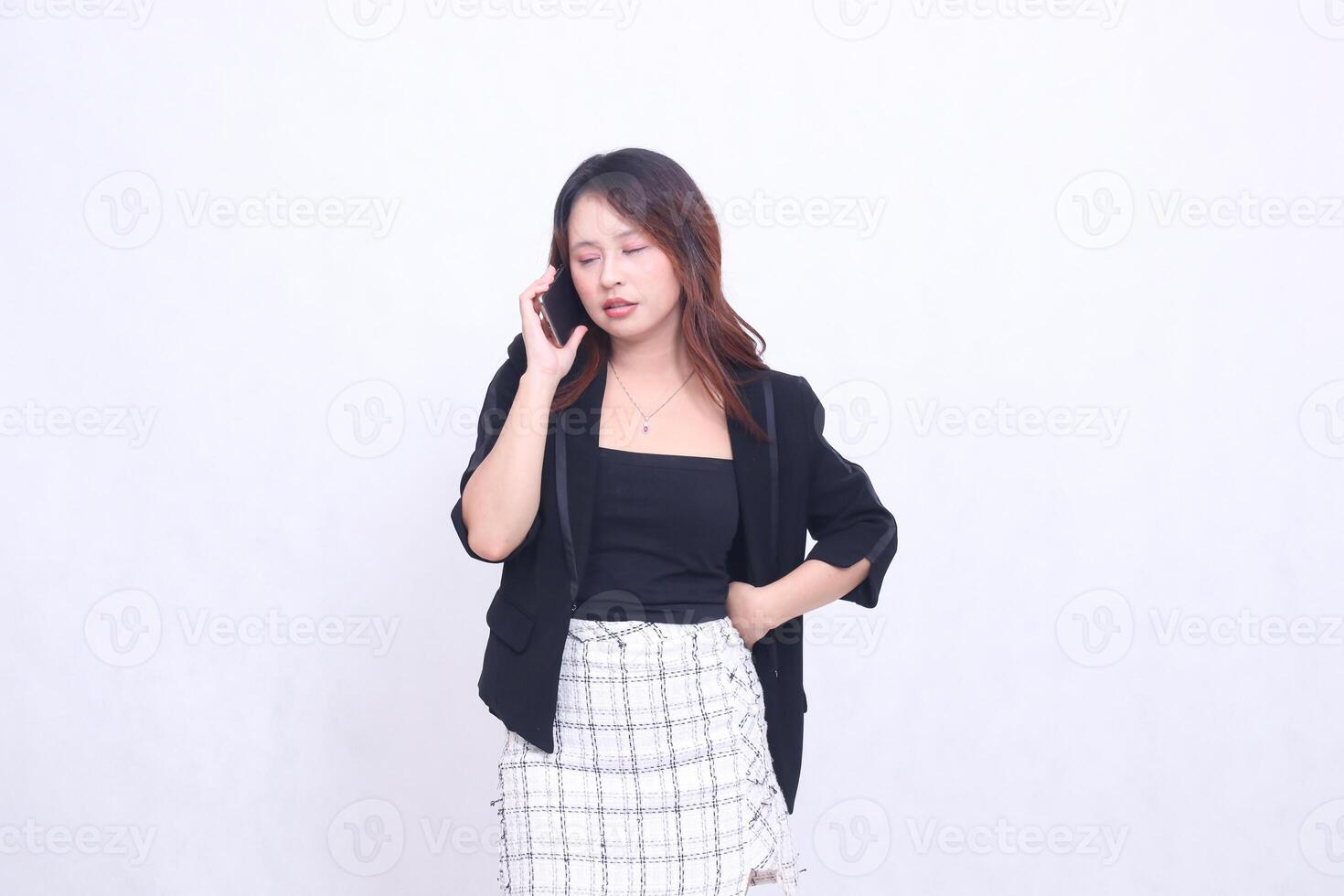 beautiful Indonesian office woman in her 20s, sleepy expression on the phone with her cellphone gadget, cream color for promo, isolated on white background photo
