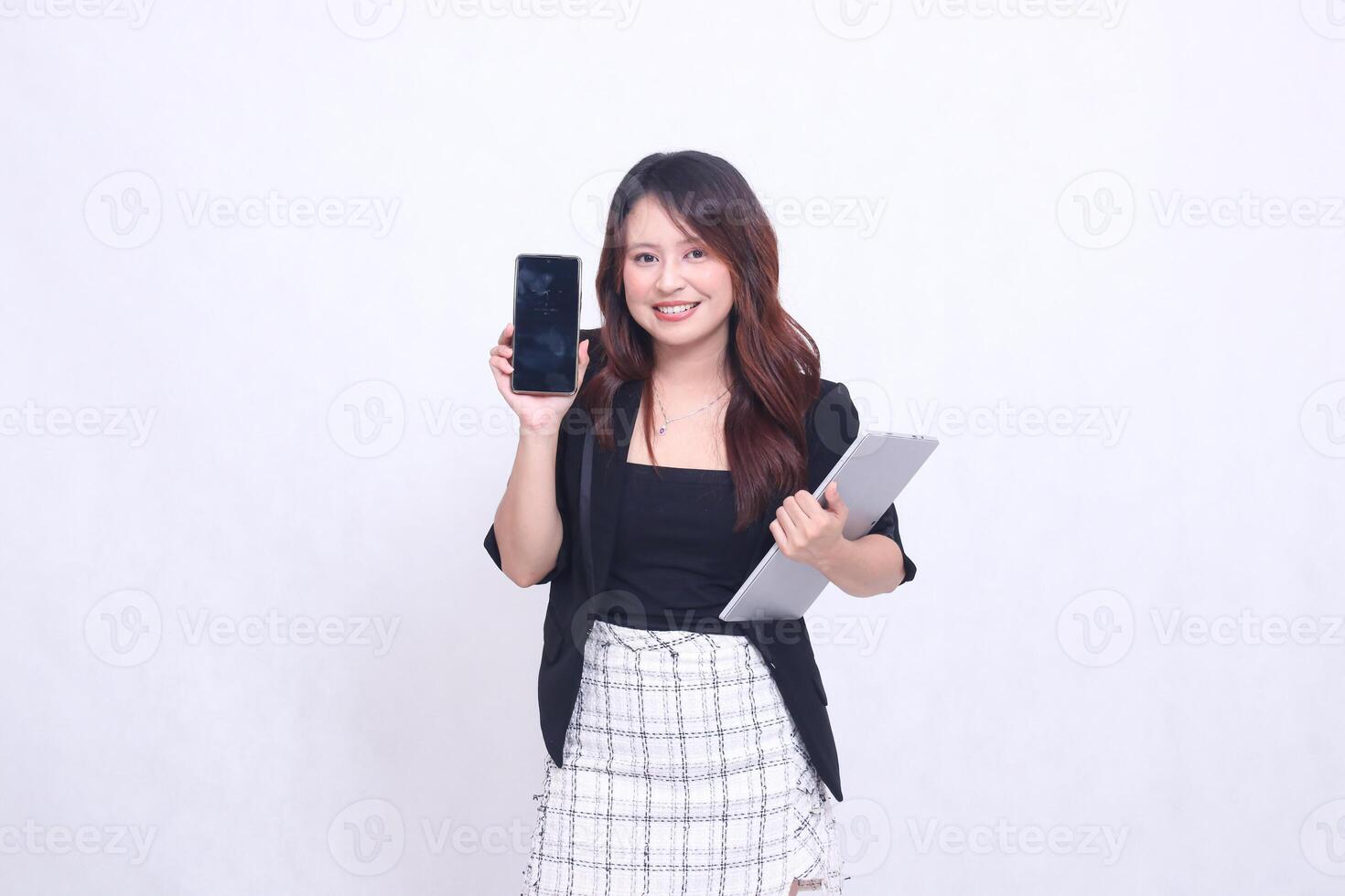 beautiful Indonesian girl 20s formal office perfect smile looking at black cellphone gadget and carrying tablet for promo isolated white background photo