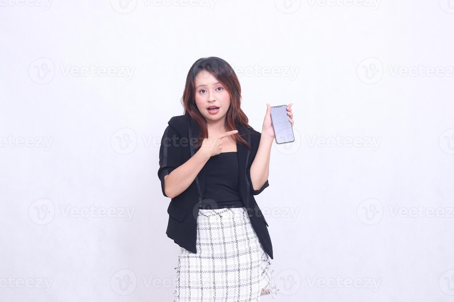 beautiful Indonesian office woman 20s expression of surprise on promotion of cellphone gadget screen for promo while pointing at it underneath isolated white background photo