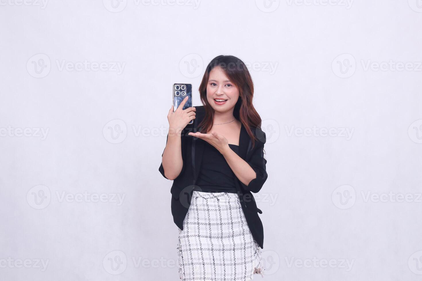 the charm of a beautiful Asian office woman in her 20s, cheerful expression, carrying a cellphone gadget facing her back while introducing her hand, isolated on a white background photo