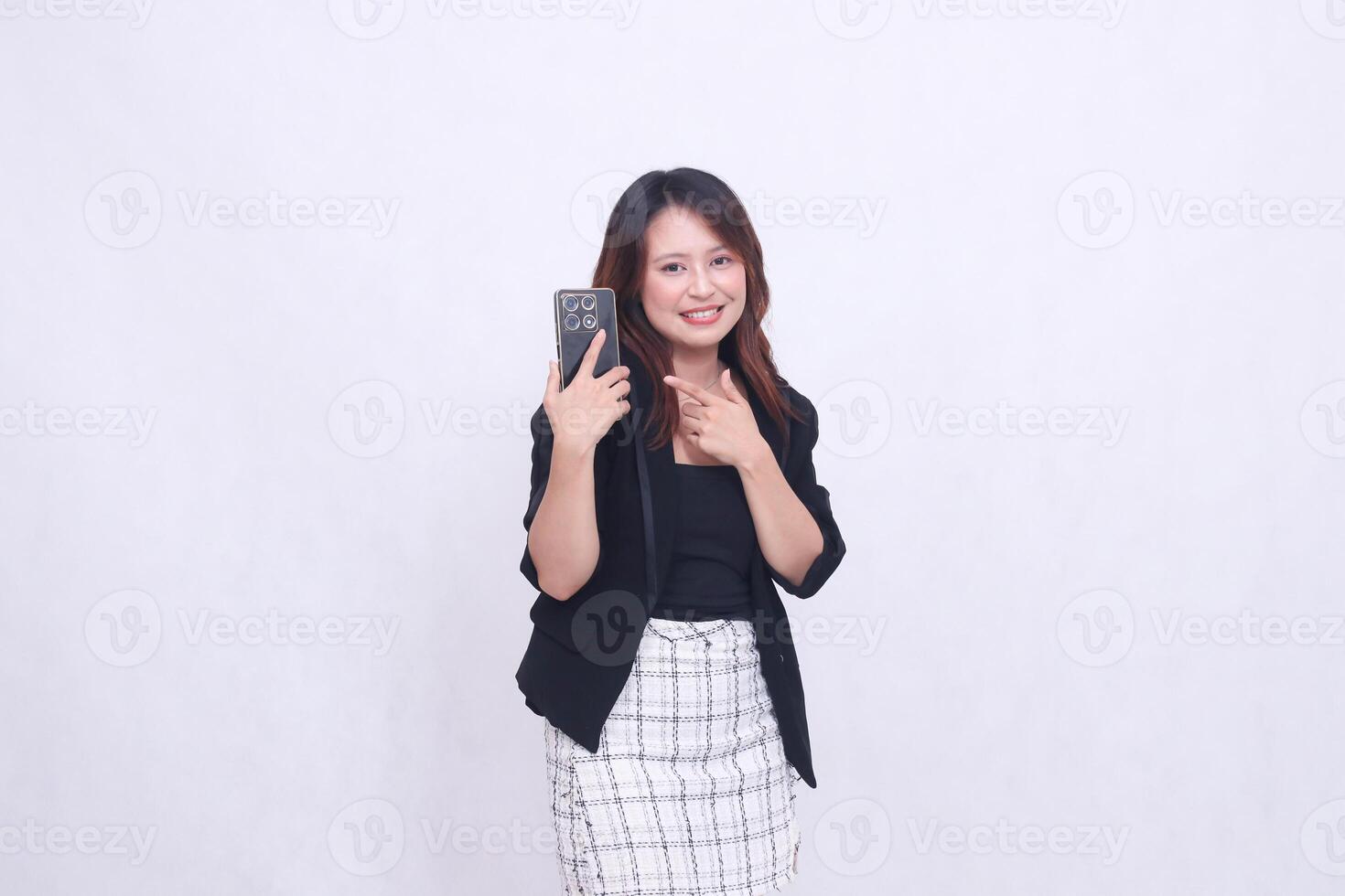 the charm of a beautiful Asian office woman in her 20s, smiling expression, carrying a cellphone gadget facing the back while pointing her hand, isolated on a white background photo
