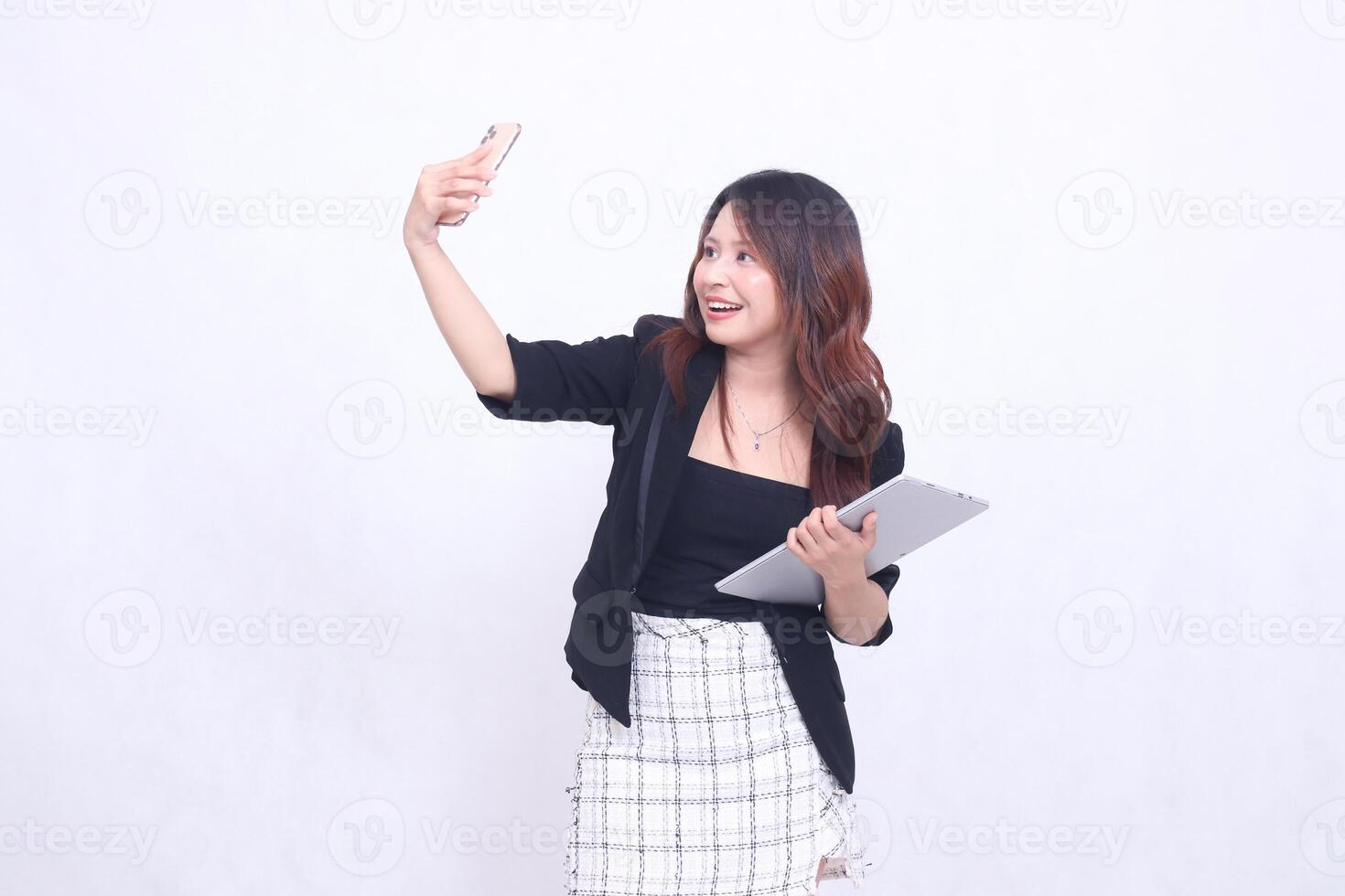 Beautiful Southeast Asian girl in her 20s, formal office, cheerful smile, making a call in front of the camera, carrying a tablet for promo, isolated on a white background photo