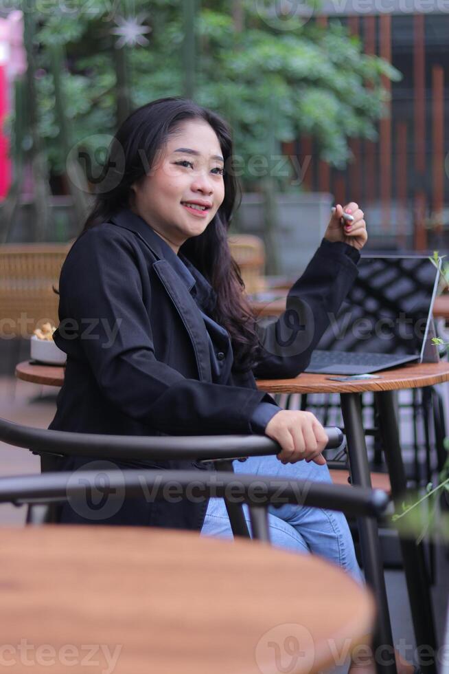 portrait of a beautiful candid Asian woman happy to get a gift from online shopping with a debit credit card at an online store holding a pen in a cafe photo