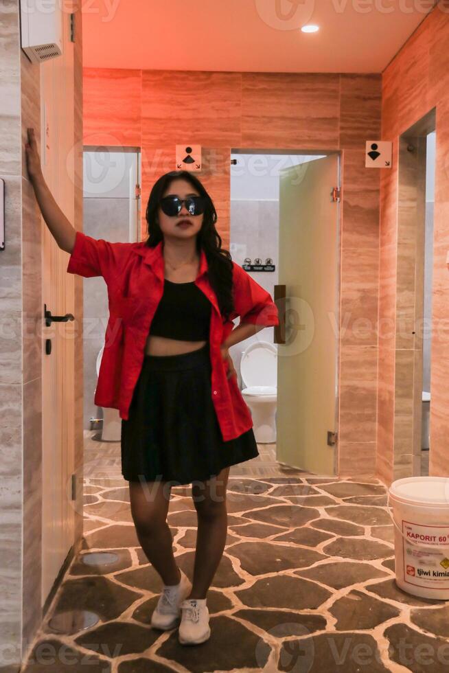 beauty of young asian woman in elegant glasses standing in front of toilet for health, fashion, science, knowledge content photo