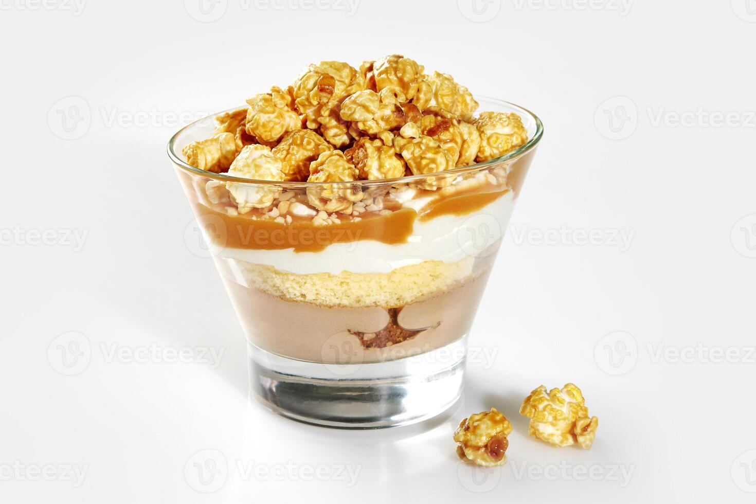 Layered trifle with sponge cake, caramel sauce and popcorn in glass photo