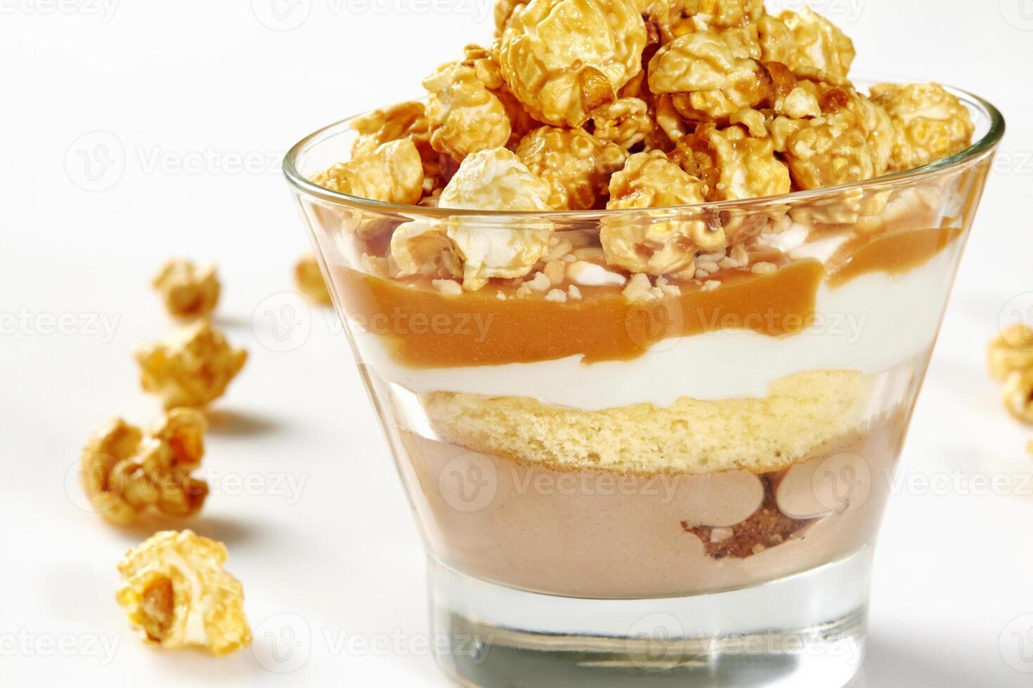 Glass of layered caramel popcorn dessert with sponge cake photo