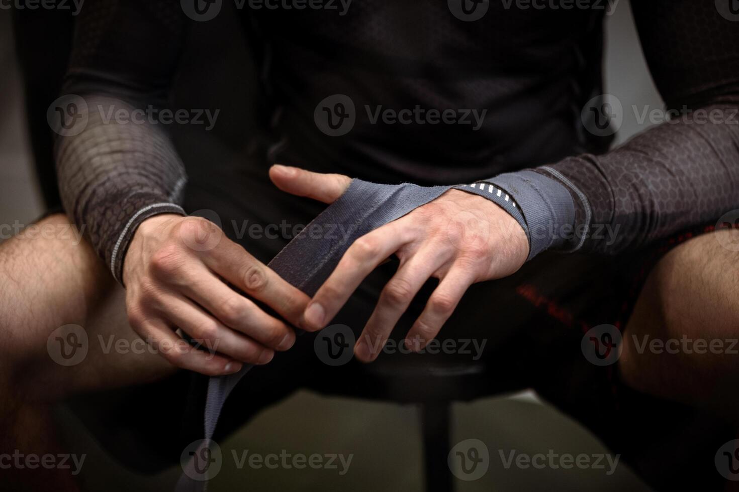 Boxer wrapping hands with boxing handwraps before training photo