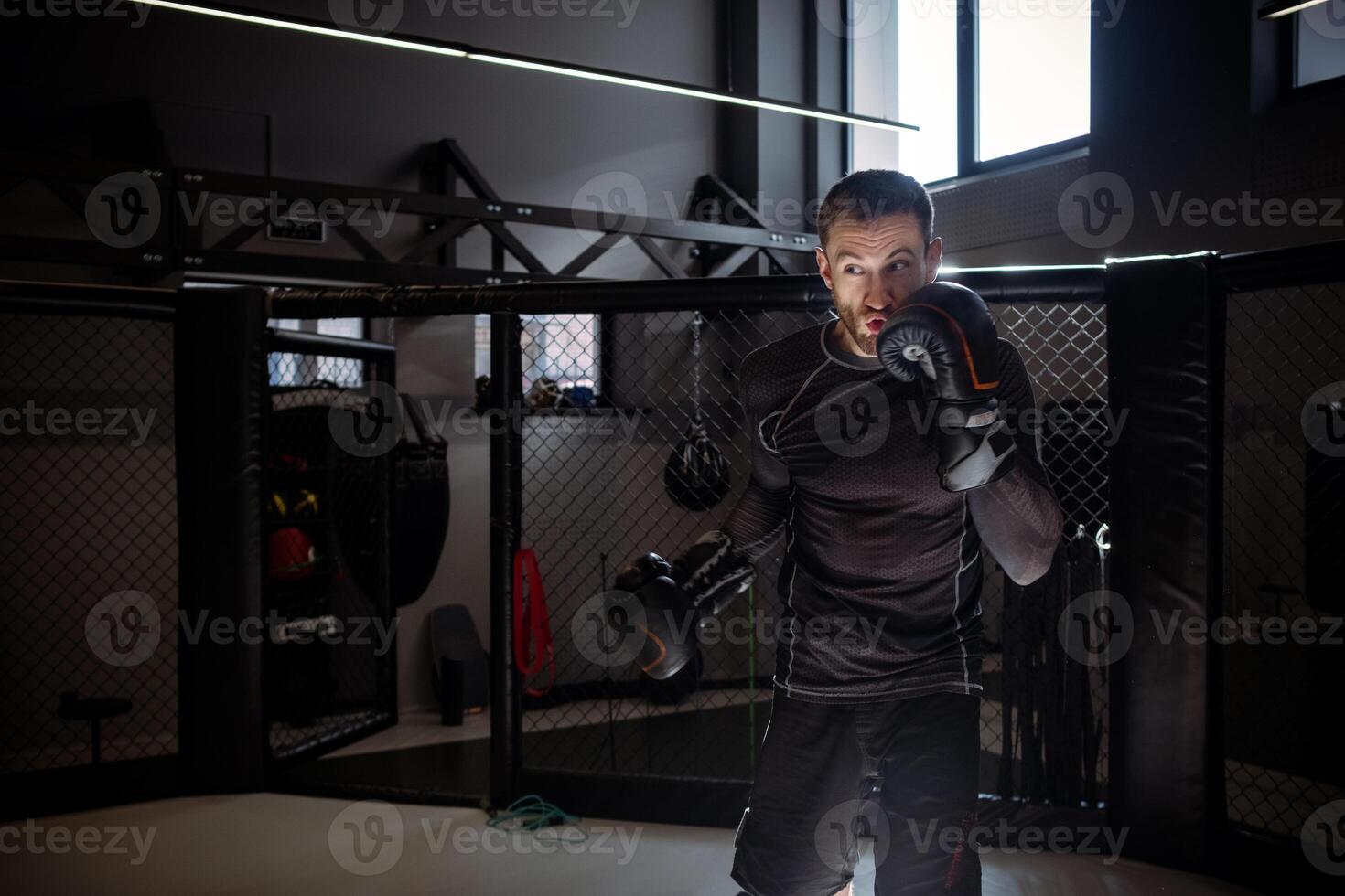 Fighter training punches during shadow fight on octagon in boxing gym photo