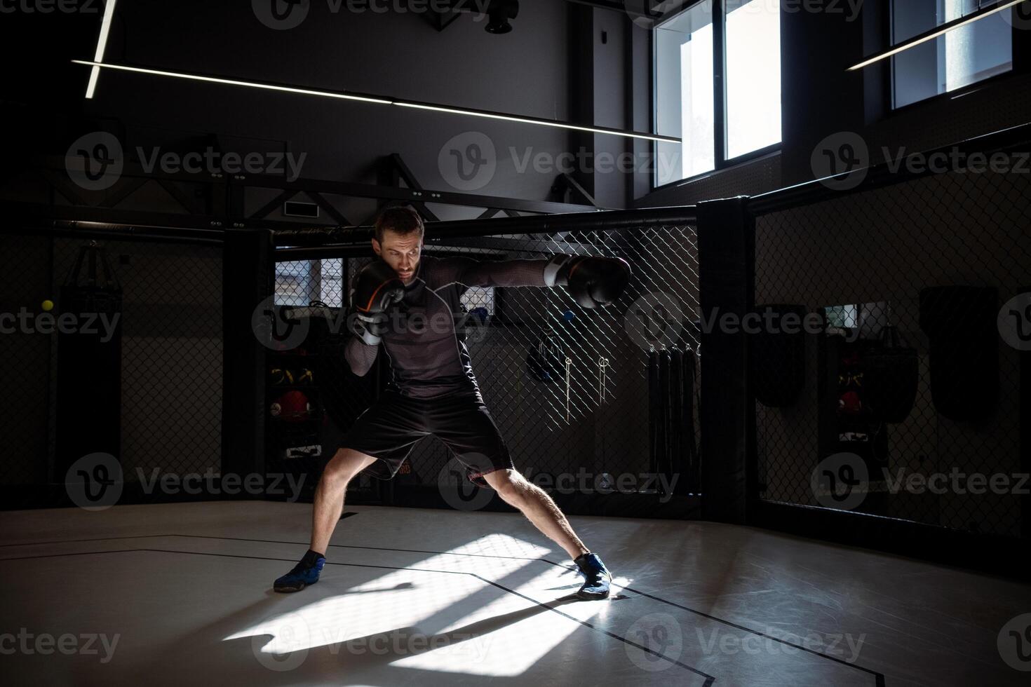 Fighter immersed in shadowboxing in rays of sunlight in boxing gym photo