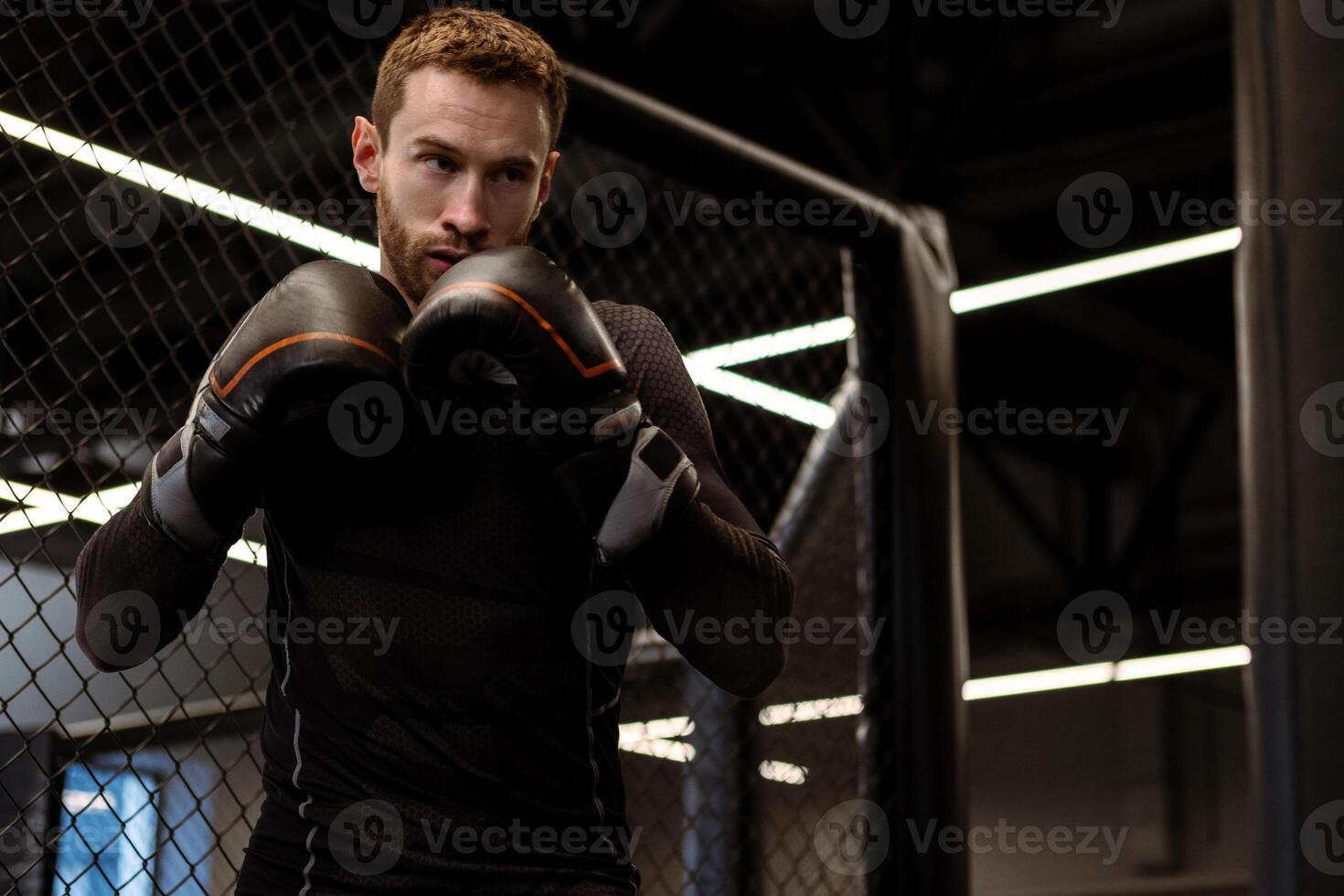 Concentrated boxer standing in fighting stance during training in gym photo