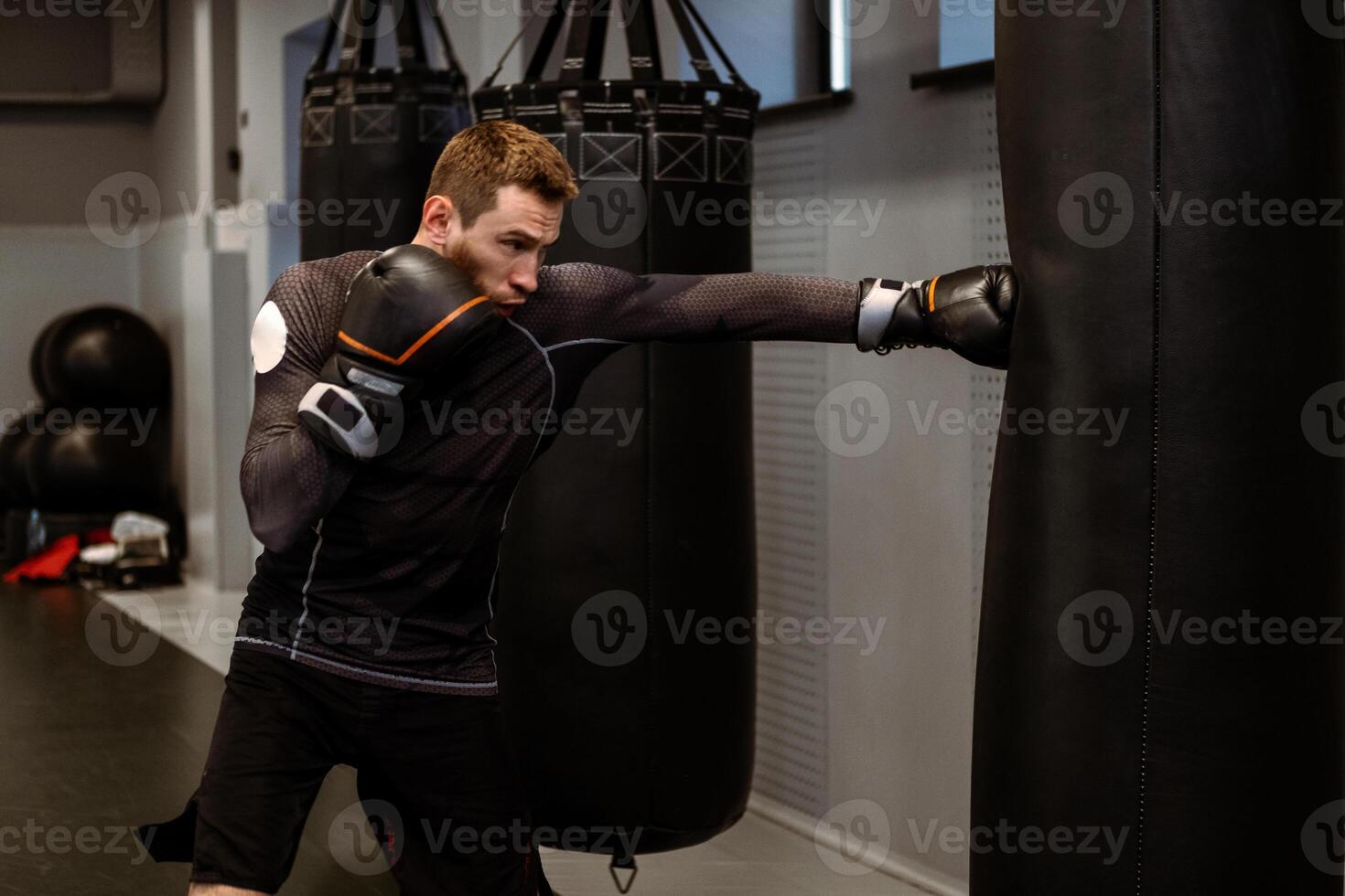 Boxer practicing on heavy bag while training in modern gym photo