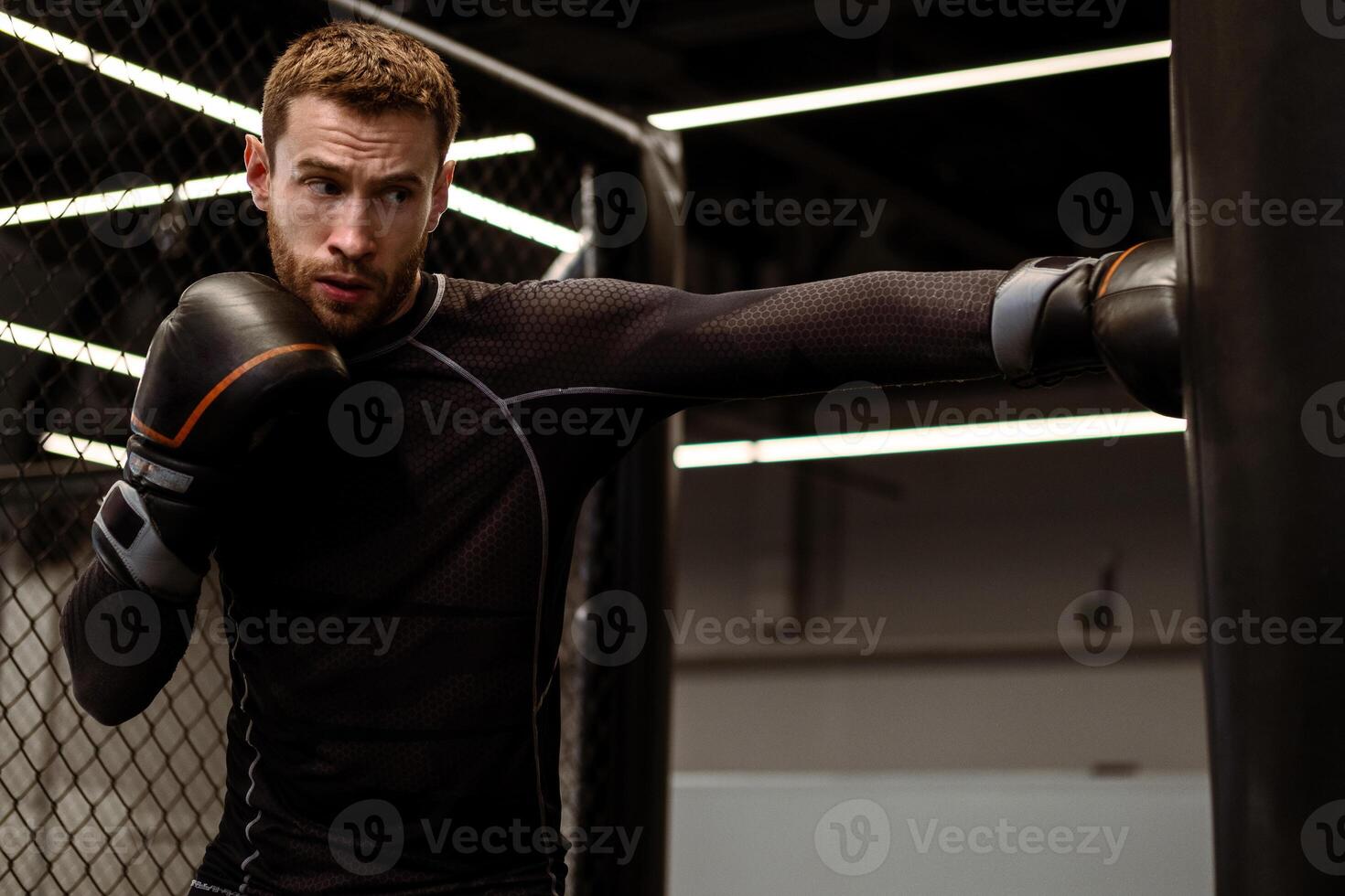 Concentrated boxer honing punching skills on heavy bag in gym photo