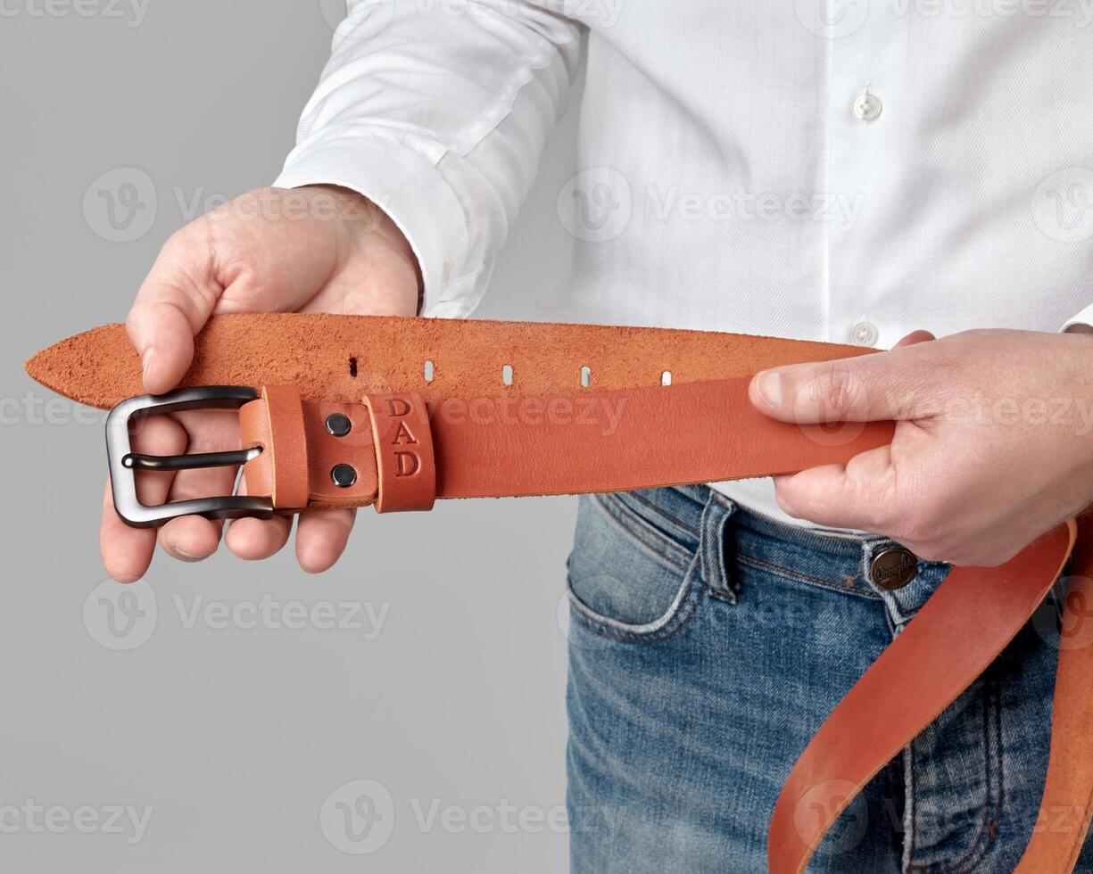 Handcrafted copper leather belt with DAD embossing in male hands photo