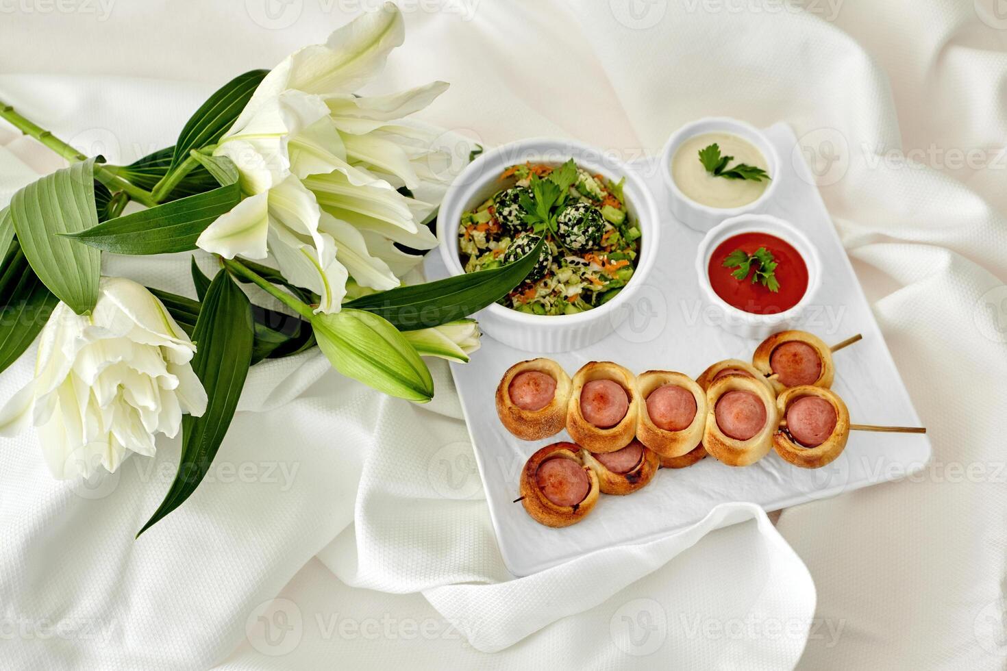 Romantic snack setting with pigs in blankets on skewers and white lilies photo