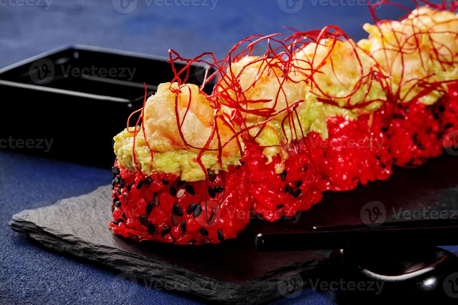 Red sushi rolls with avocado, shrimp and togarashi threads photo