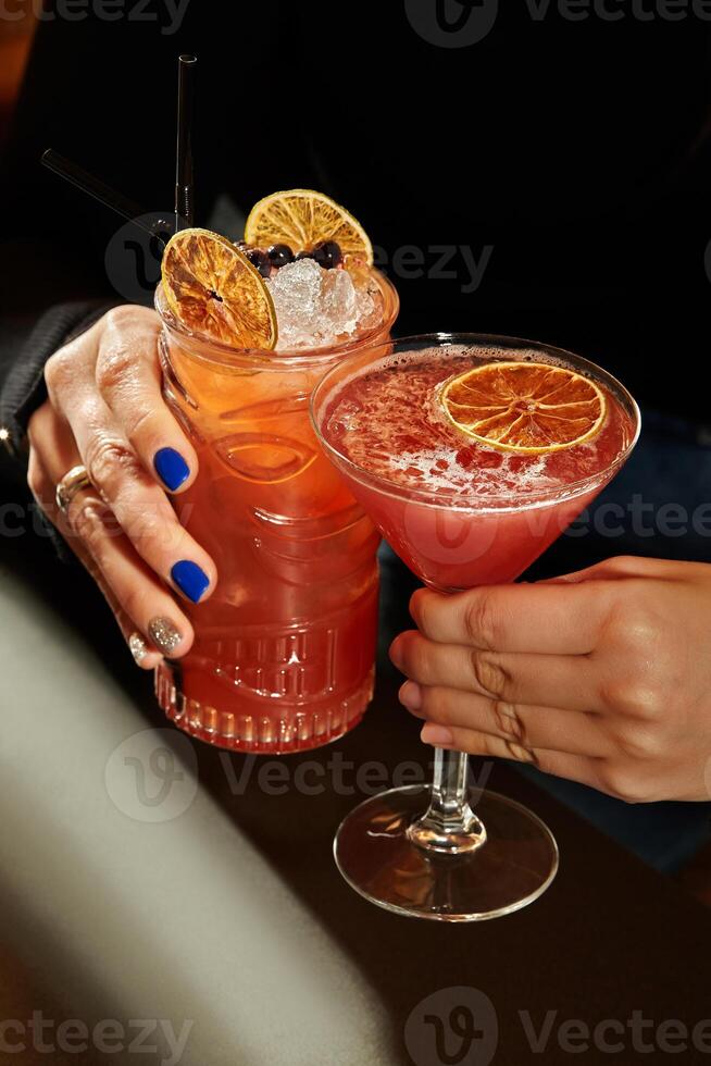 Female hands with glasses of beautifully garnished light cocktails photo
