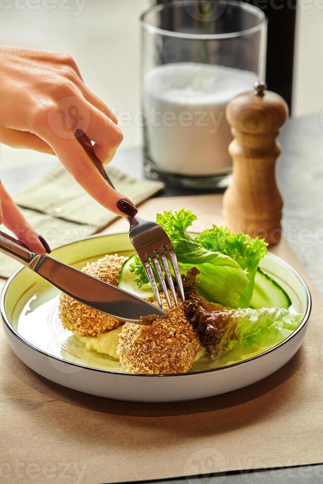 Woman enjoying breaded chicken patties with salad and mashed potatoes photo