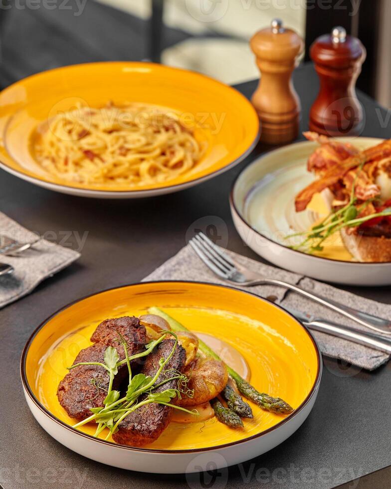 Plate with steak, baked potato and asparagus on table set for dinner photo