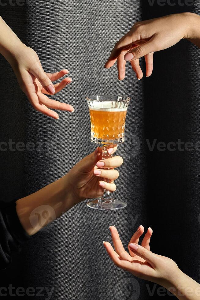 Female hands hovering around crystal glass of whiskey sour photo