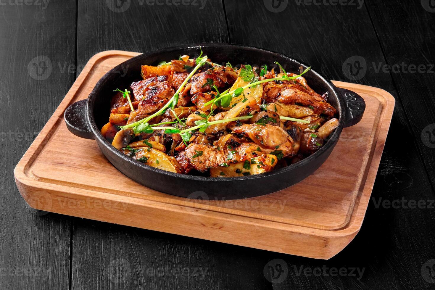Roasted pork chuck with mushrooms, potatoes, onions and greens in frying pan photo