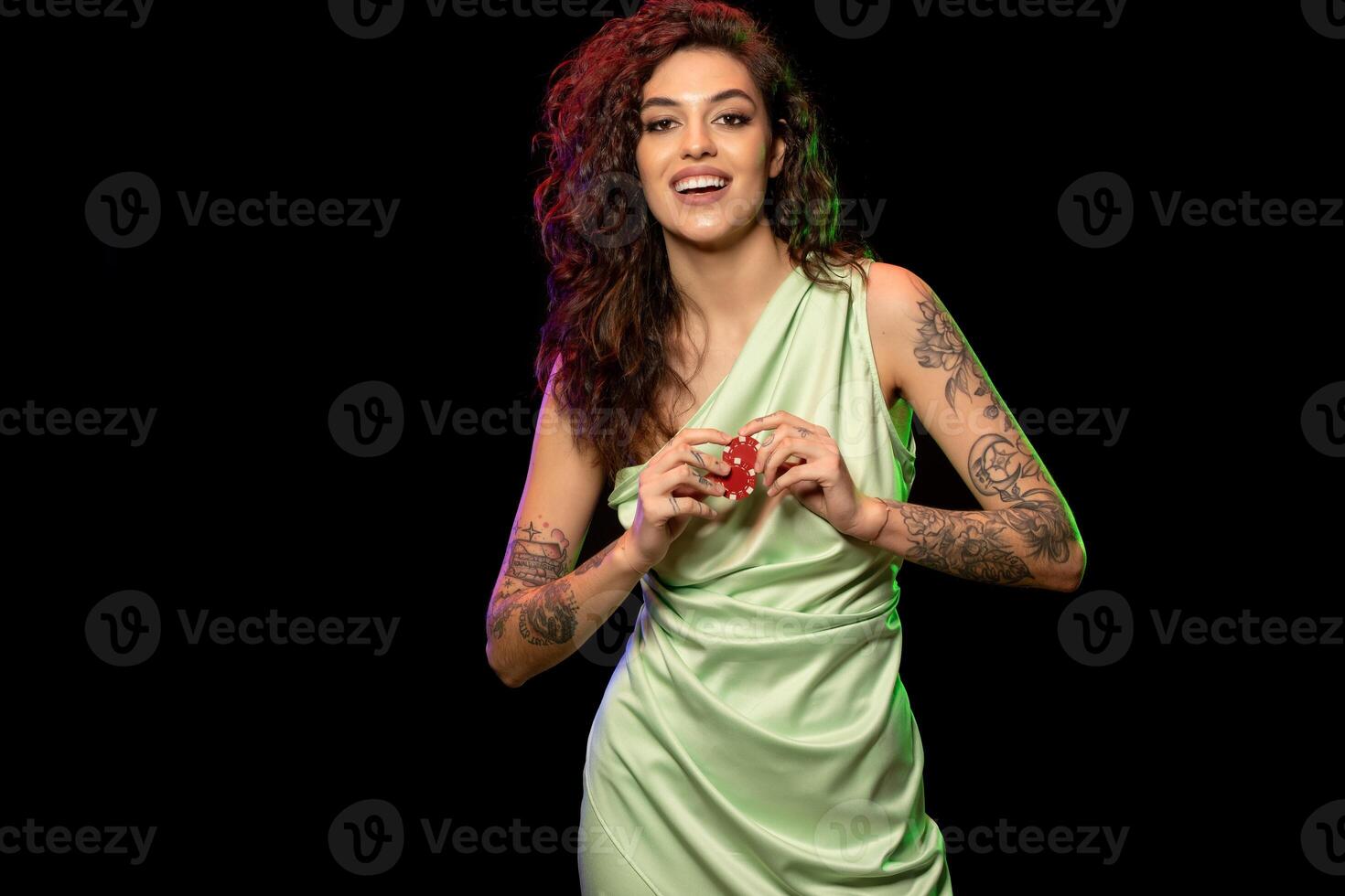 Cheerful stylish young girl holding two red betting chips photo
