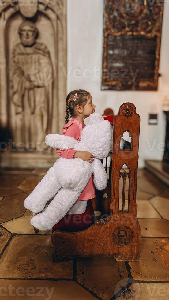 Little girl playing with his toy in catholic church. photo
