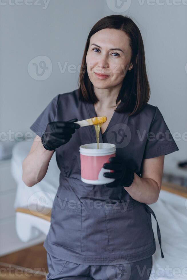 Depilation master shows shugaring depilation spatulas in his hands photo