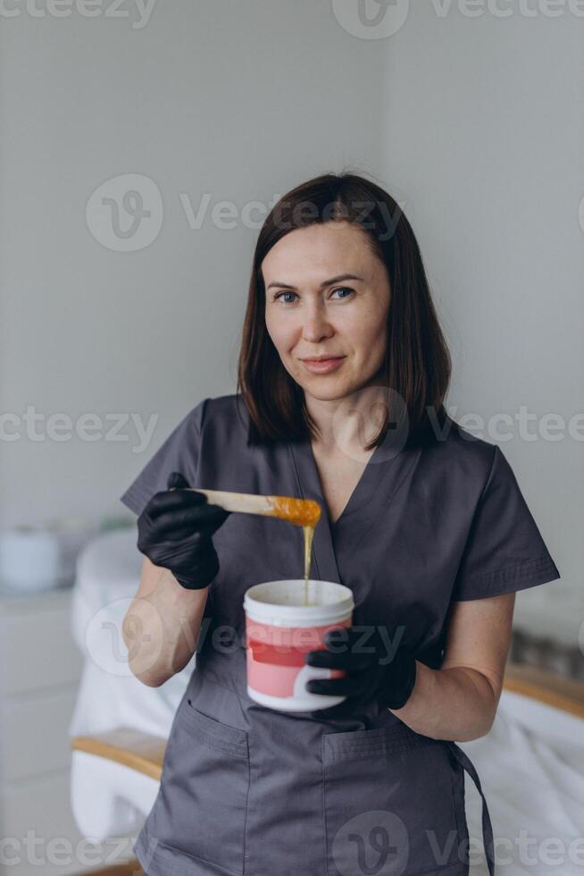 Depilation master shows shugaring depilation spatulas in his hands photo