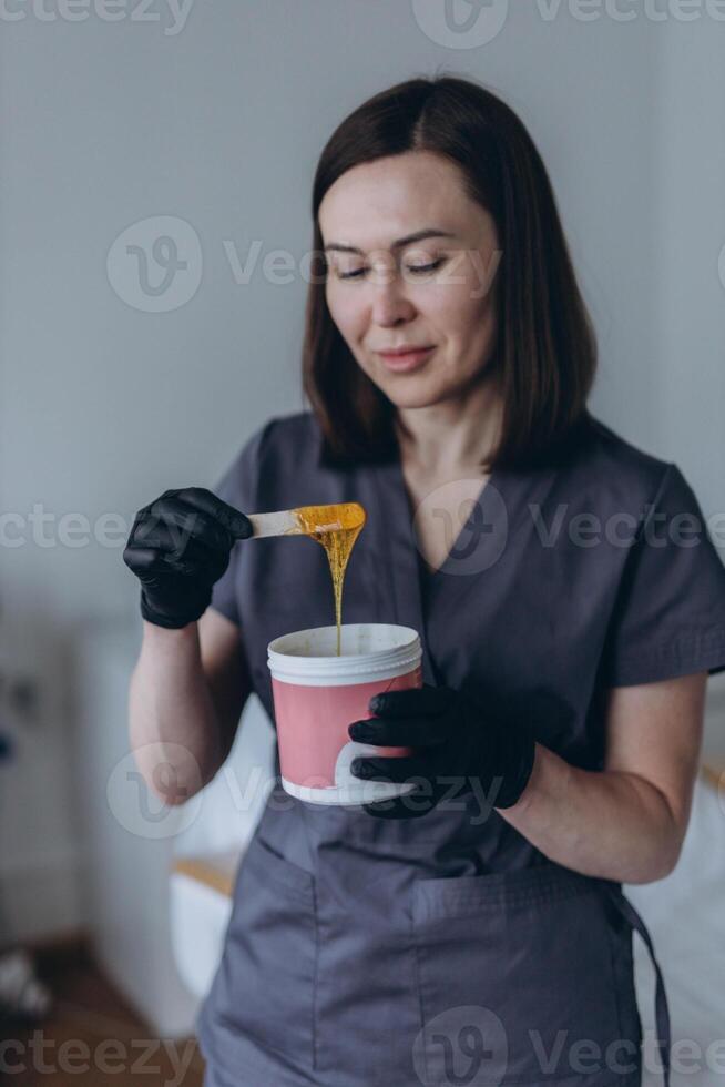 Depilation master shows shugaring depilation spatulas in his hands photo