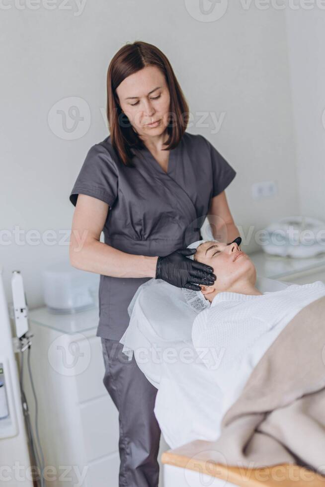 portrait of a young attractive woman getting facial massage with cream. photo