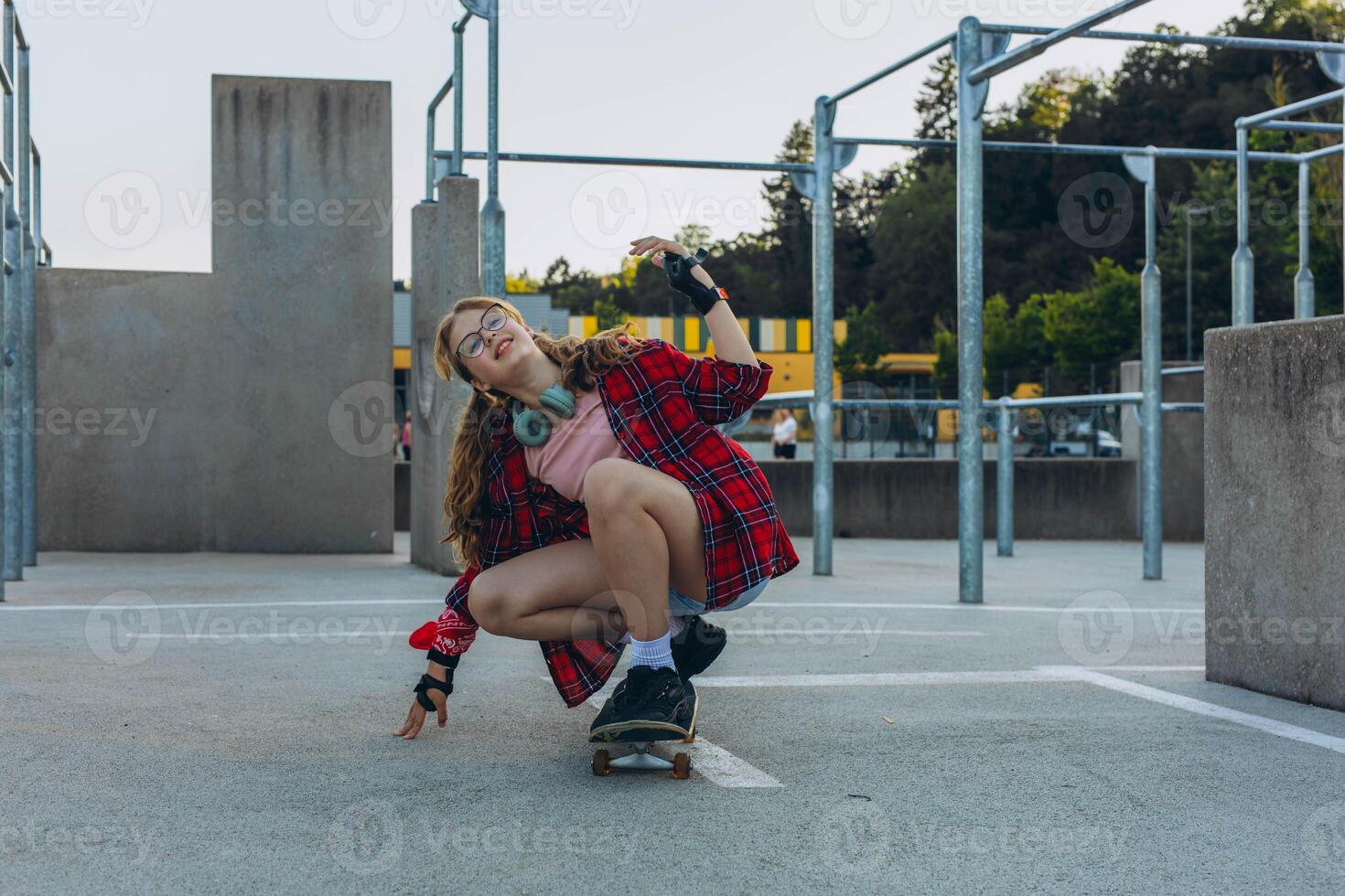 Teen girl skater with a skateboard is sitting and resting in the skaters park photo