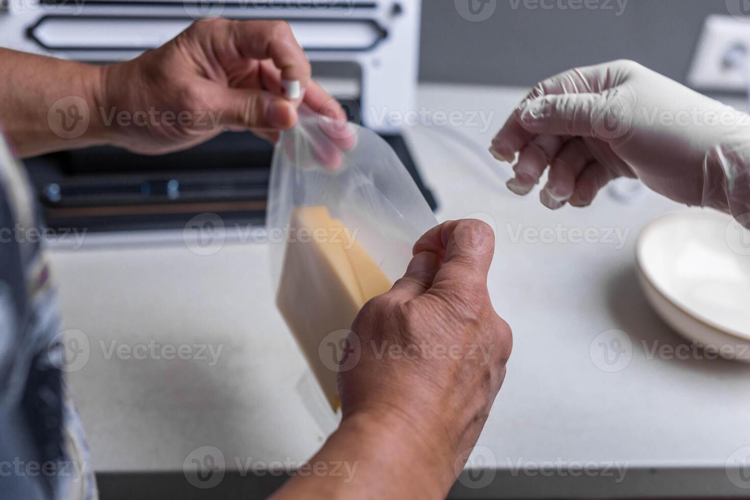 Close-up of men's hands sealing cheese into an airtight bag using a vacuum sealer photo