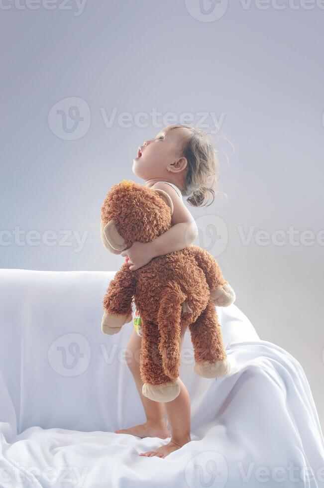 An Indonesian little girl very happy while holding her lovely doll. Look up photo