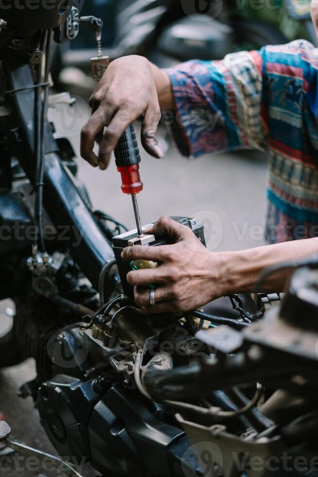 A motorcycle mechanic inspecting a damaged bikeA motorcycle mechanic is checking a damaged engine photo