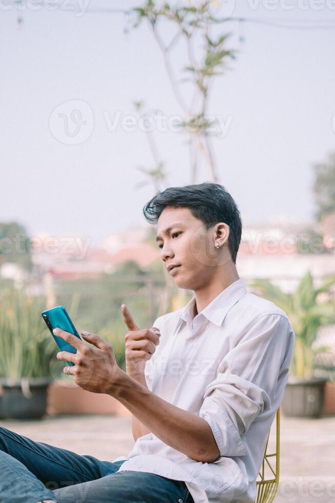 A man points at his smartphone with a suspicious look, questioning what's happening photo
