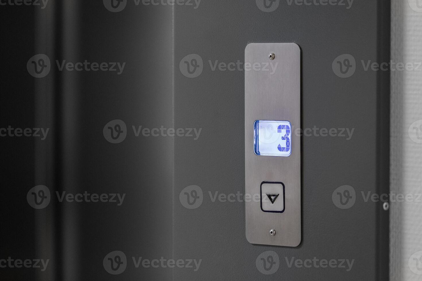 Metal panel with an elevator call button and an indicator of the floor on which the elevator car is located in blue photo