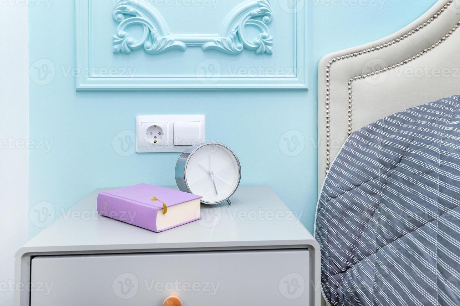 Alarm clock with a book on the bedside table photo