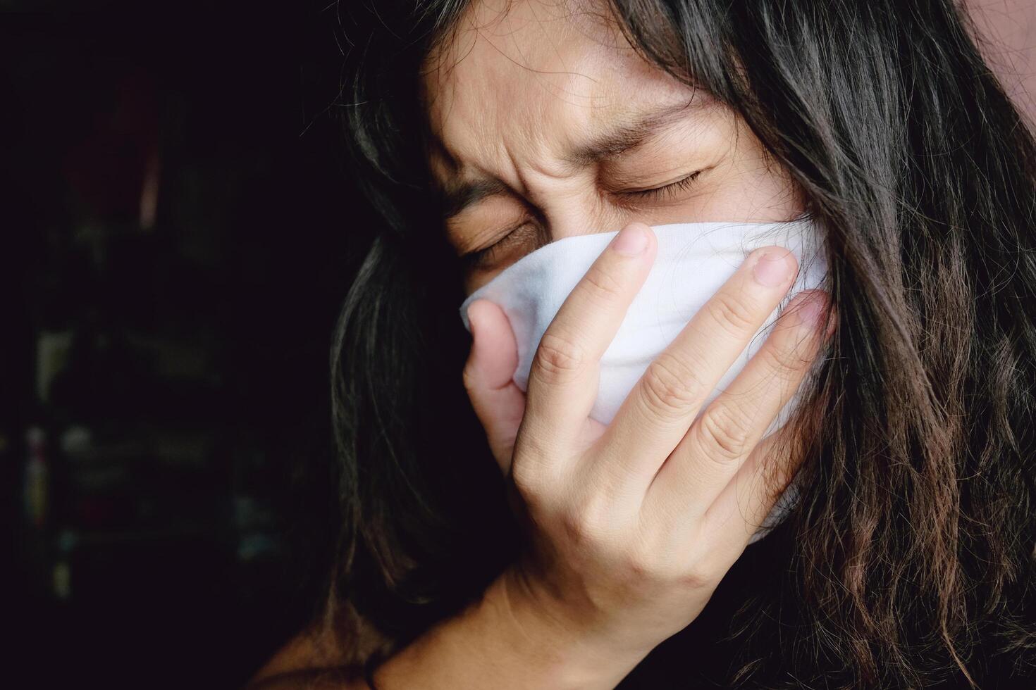 Asian Thai woman wearing a white cloth mask for prevent the Covid-19 or Corona virus in Thailand. She is serious and Coughing about Air Pollution Value Pm 2.5. Health and Respiratory system concept photo