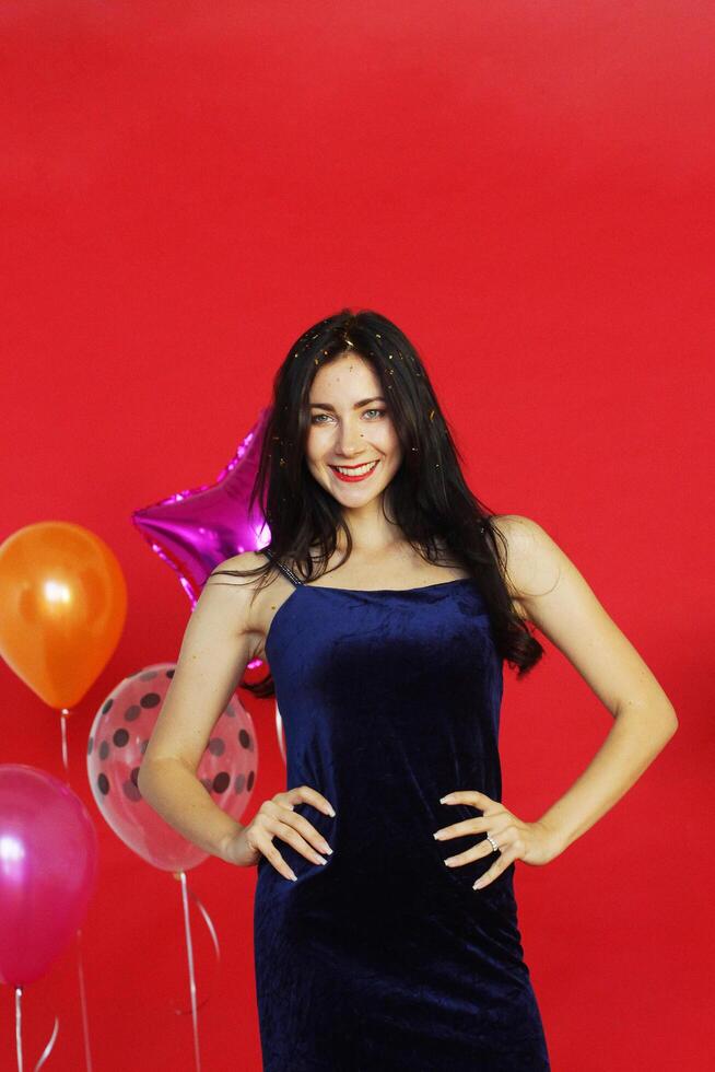 Beautiful Woman Smile and dancing in Chrismas party, birthday time and celebration of New year eve and decoration with colorful ballons and on red background photo