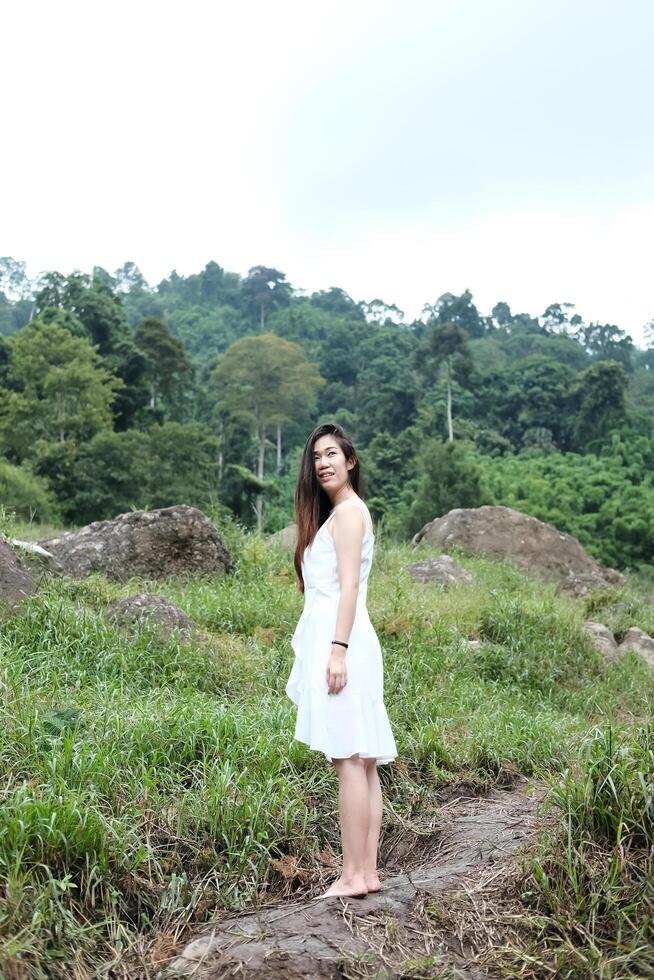 Smiling Asian woman standing on the rocky in natural greenland and stream in forest. photo