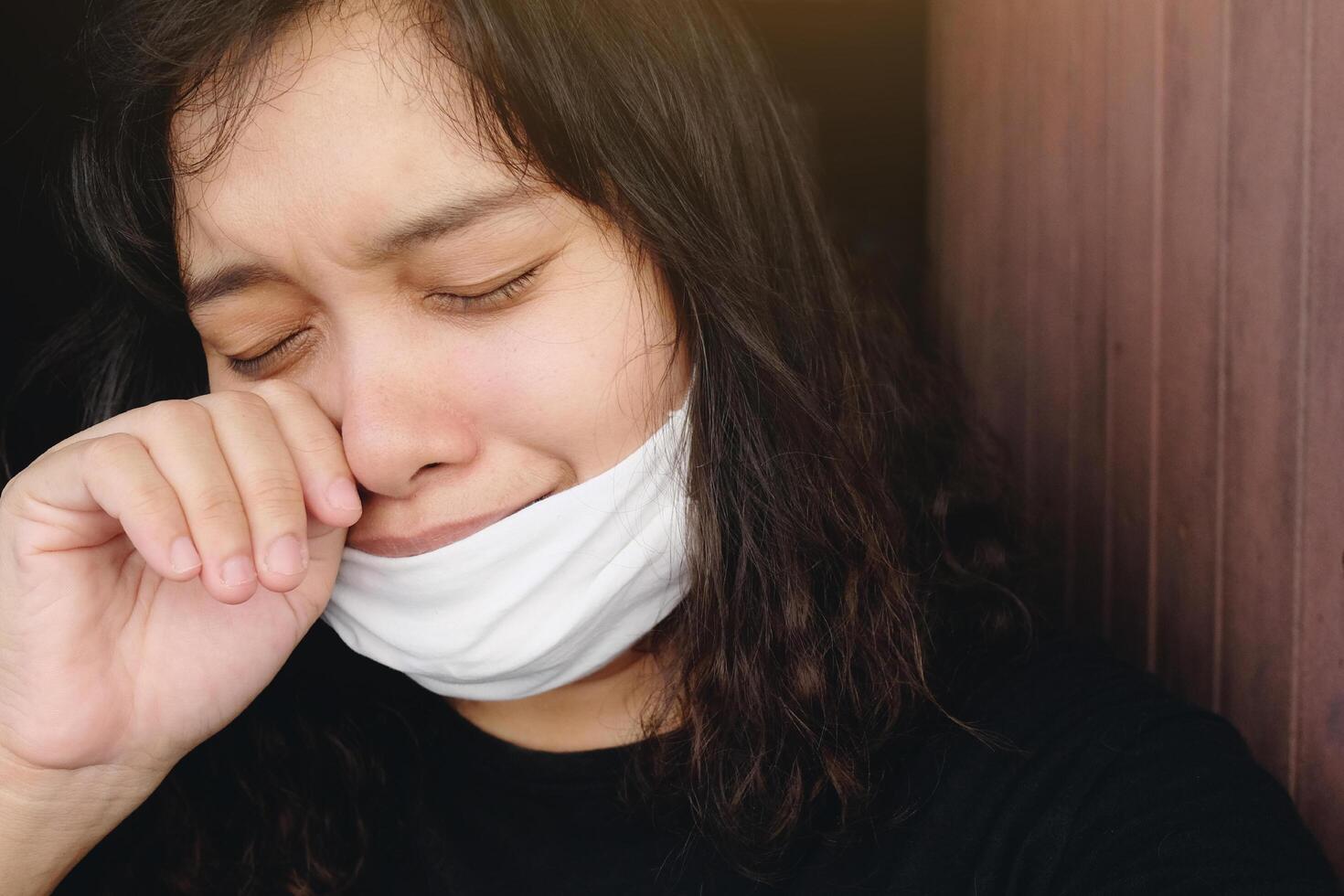 Asian Thai woman wearing a black cloth mask for prevent the Covid-19 or Corona virus and Epidemic disease at Thailand and around the world. She is coughing and headache. Health and illness concept photo