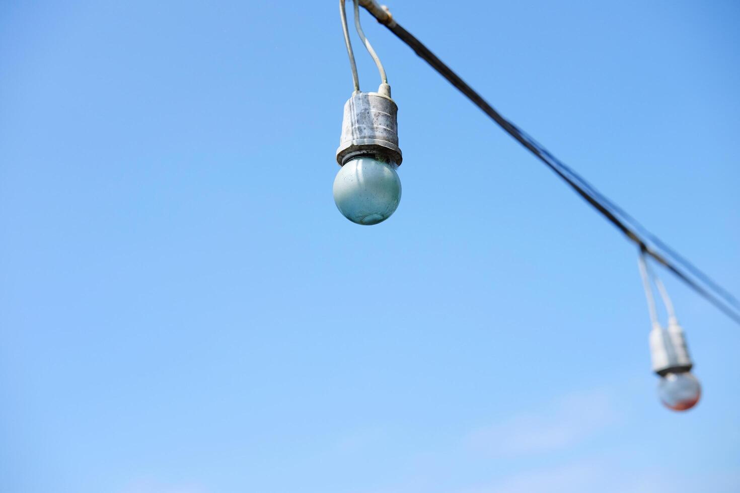 Equipped and electrical with light bulbs is hanging in the wind and sunlight on blue sky photo