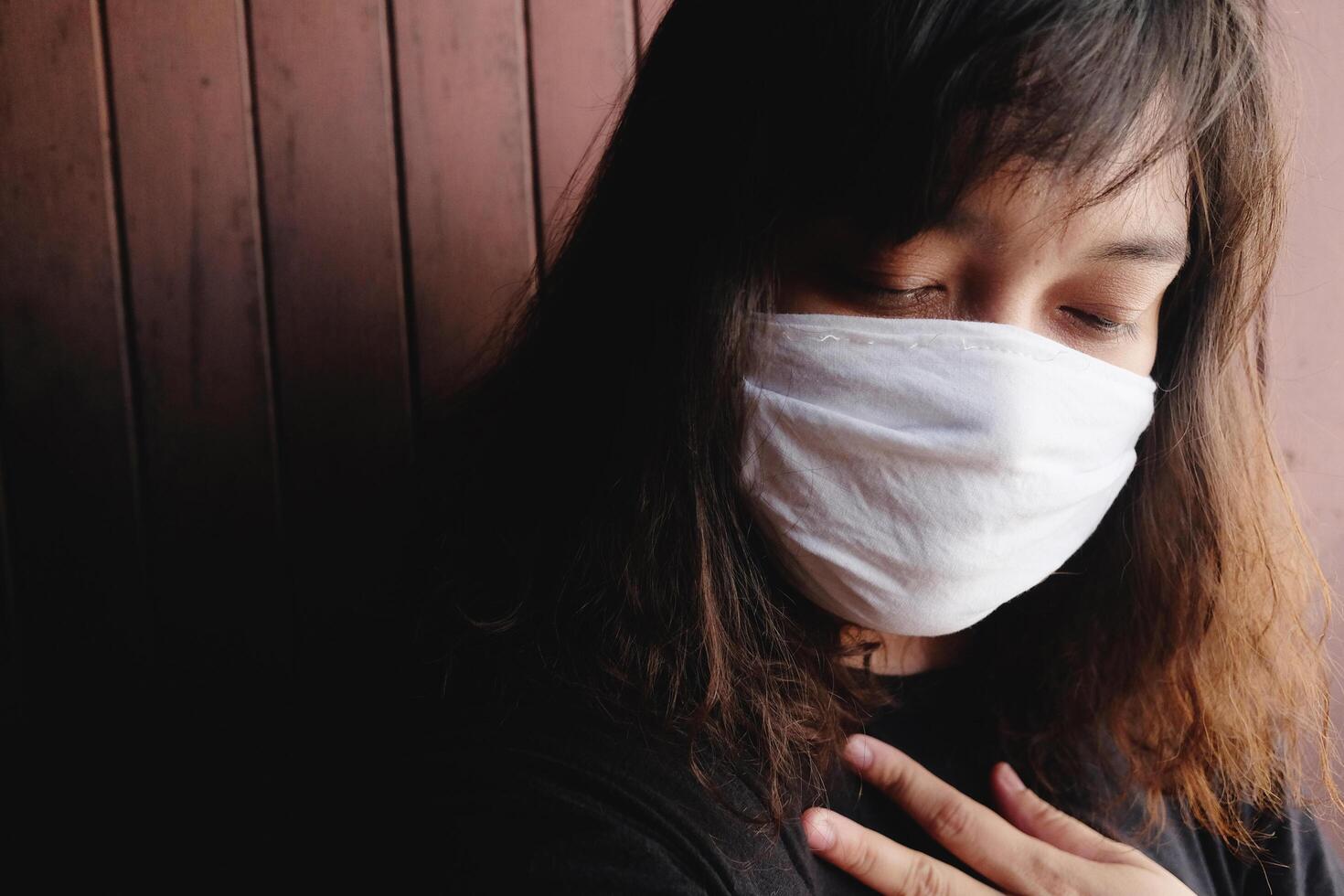 Asian Thai woman wearing a white cloth mask for prevent the Covid-19 or Corona virus and Air Pollution Value Pm 2.5 in Thailand. She is suffocating in Respiratory system. Health and illness concept photo